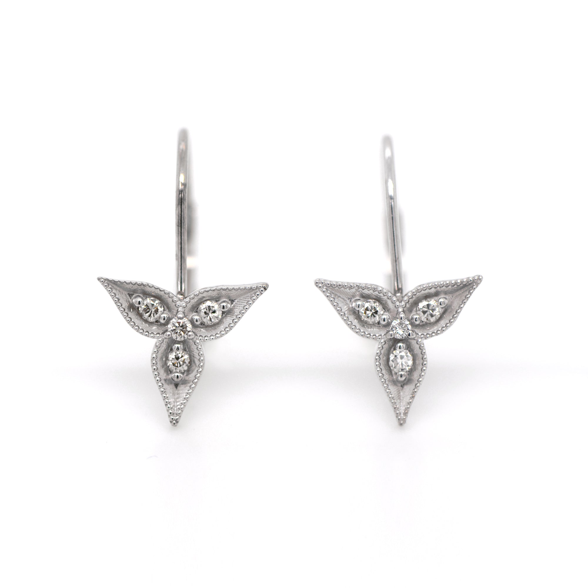 14K white gold diamond drop earrings featuring 12 round brilliant diamonds (0.12ctw) set in a 3-petal trillium flower design.