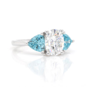 Judith Arnell Jewelers 14K white gold moissanite and zircon ring featuring one 2.00 carat oval moissanite, and 2 trillion-cut blue zircons weighing a total of 2.32 carats set in a 3-stone design.