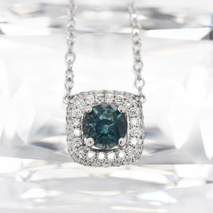 18-inch 18K white gold blue-green sapphire and diamond necklace featuring one round 1.63 carat blue-green sapphire, and round brilliant diamonds set in a cushion shaped halo and 8 bezel-set diamonds set along the chain. 