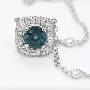 18-inch 18K white gold blue-green sapphire and diamond necklace featuring one round 1.63 carat blue-green sapphire, and round brilliant diamonds set in a cushion shaped halo and 8 bezel-set diamonds set along the chain. 