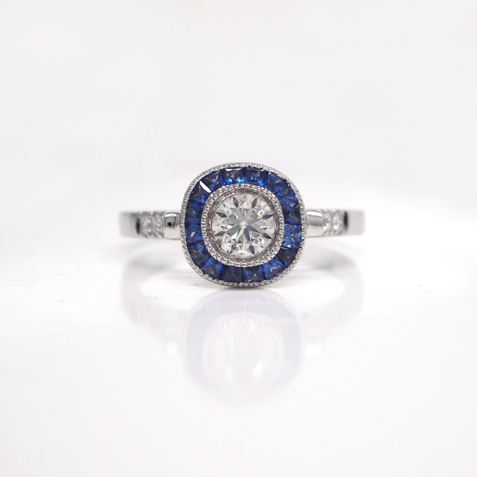 18K white gold sapphire and diamond engagement ring with one 0.42 carat round brilliant-cut diamond, baguette-cut sapphires weighing a total of 0.42 carats, and round brilliant-cut diamond weighing a total of 0.07 carats. 