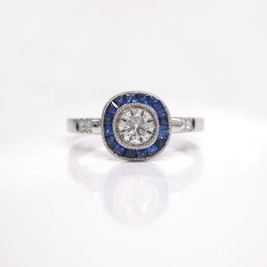 18K white gold sapphire and diamond engagement ring with one 0.42 carat round brilliant-cut diamond, baguette-cut sapphires weighing a total of 0.42 carats, and round brilliant-cut diamond weighing a total of 0.07 carats. 