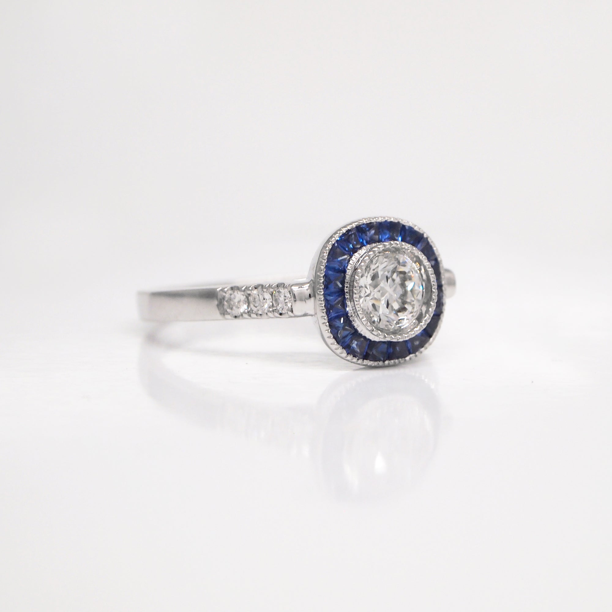 18K white gold sapphire and diamond engagement ring with one 0.42 carat round brilliant-cut diamond, baguette-cut sapphires weighing a total of 0.42 carats, and round brilliant-cut diamond weighing a total of 0.07 carats. 