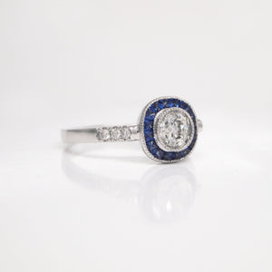 18K white gold sapphire and diamond engagement ring with one 0.42 carat round brilliant-cut diamond, baguette-cut sapphires weighing a total of 0.42 carats, and round brilliant-cut diamond weighing a total of 0.07 carats. 