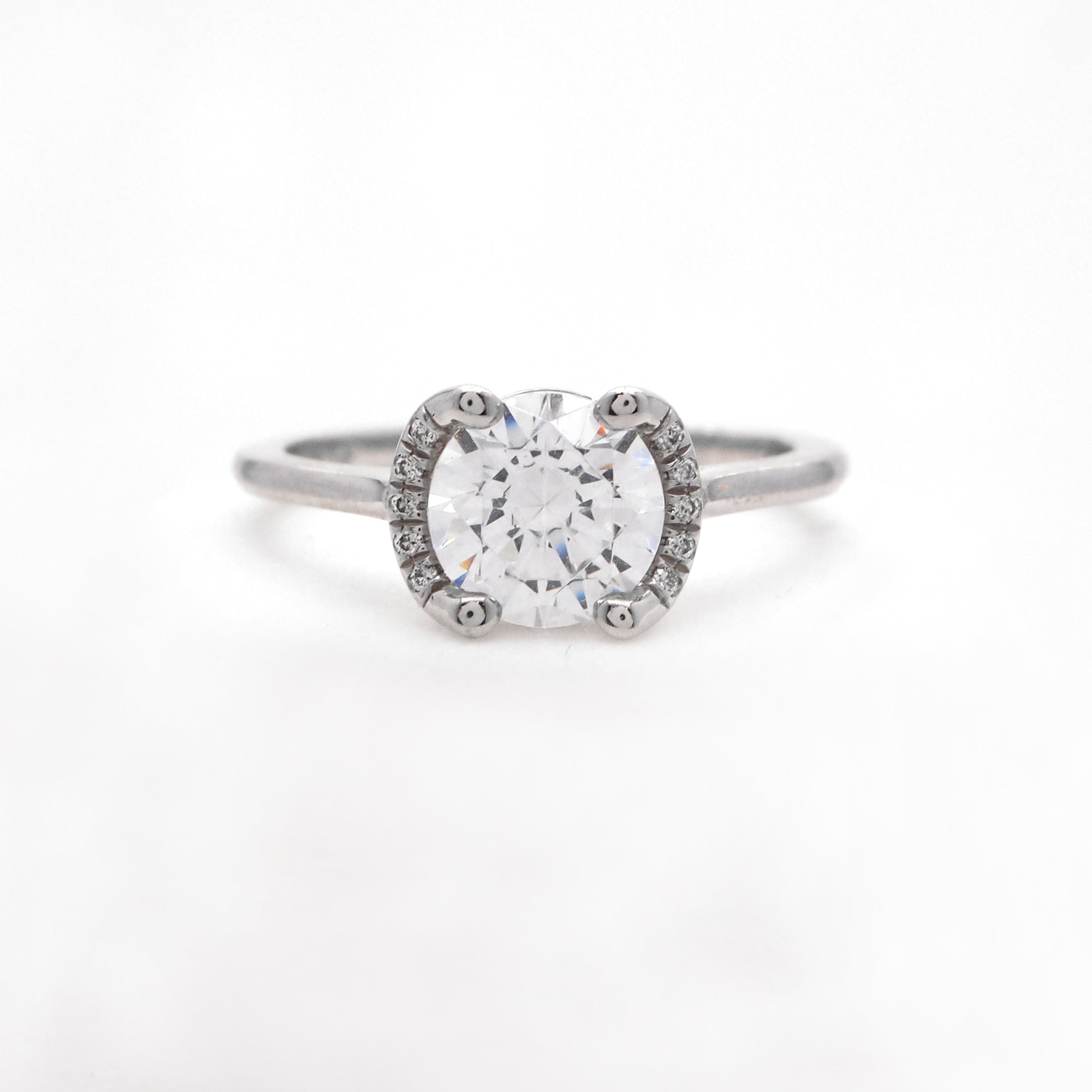 Platinum engagement ring featuring a crescent halo with round brilliant diamonds weighing a total of 0.04 carats. This