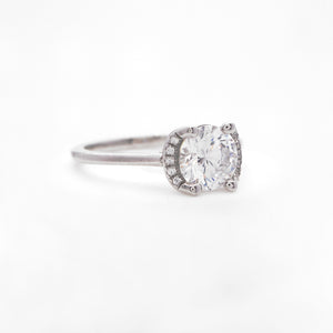 Platinum engagement ring featuring a crescent halo with round brilliant diamonds weighing a total of 0.04 carats. This