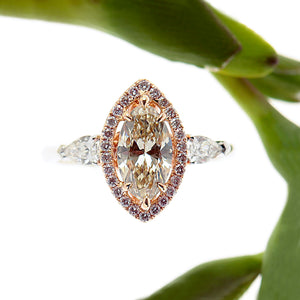 14K white gold diamond engagement ring featuring 1 champagne marquis diamond in a halo of round brilliant pink diamonds, and 2 pear shaped diamond set in a 3-stone design. By Judith Arnell Jewelers.