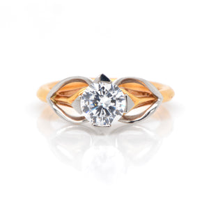 Round brilliant-cut solitaire named after the Scottish island of Eriskay with a platinum and rose gold setting and heart-shaped shoulders, flowing around a swan-neck shank. 