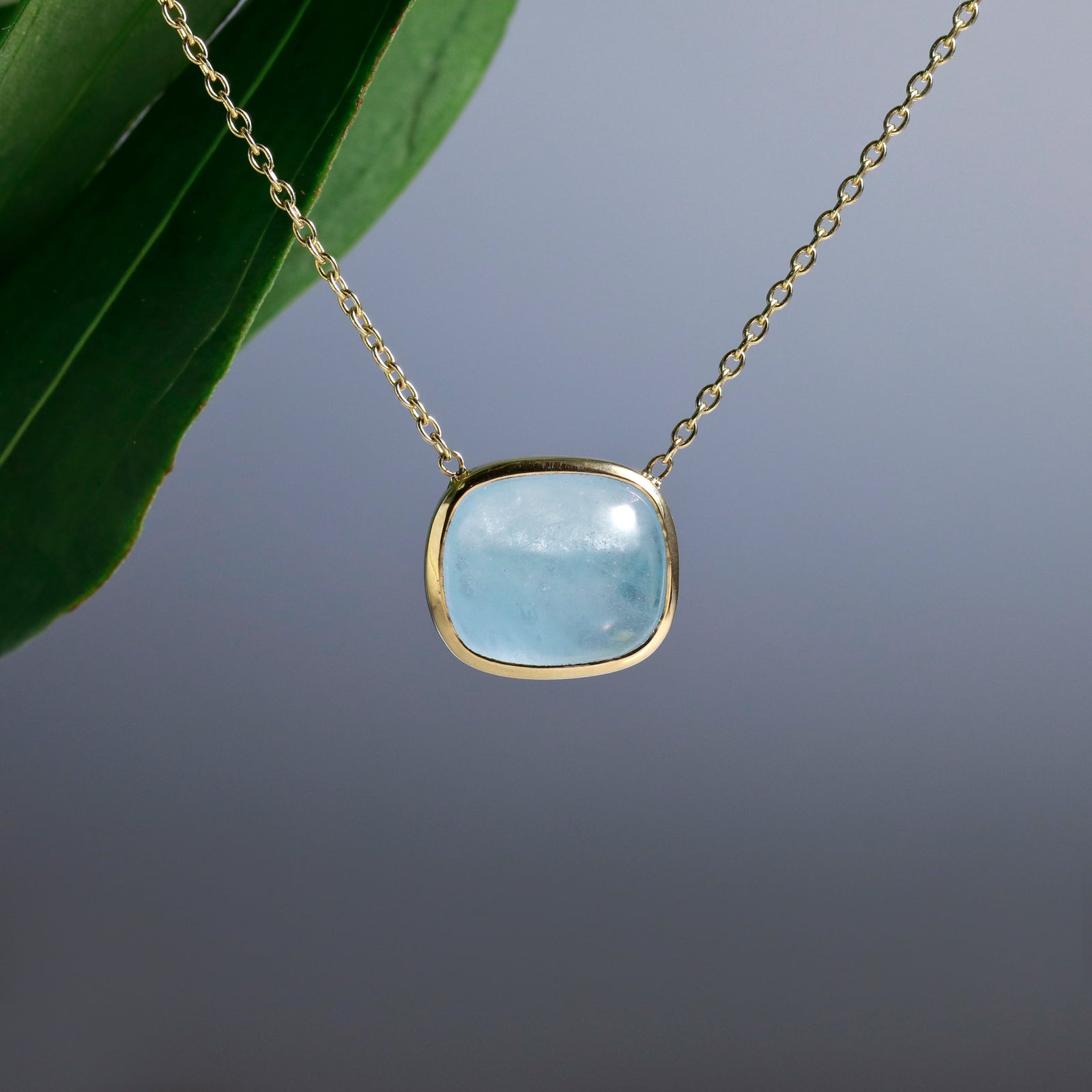 14K yellow gold aquamarine necklace featuring 1 cabochon-cut blue aquamarine weighing 12.33 carats in a bezel setting.