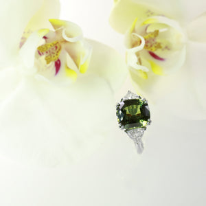 Platinum 3-stone natural sapphire and diamond ring featuring one 7.07 natural green-yellow sapphire, and two trillion diamonds weighing a total of 1.09 carats.