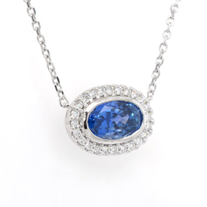 14K white gold sapphire and diamond necklace featuring one 2.90 carat oval blue sapphire set East-West in a diamond halo (0.24ctw).
