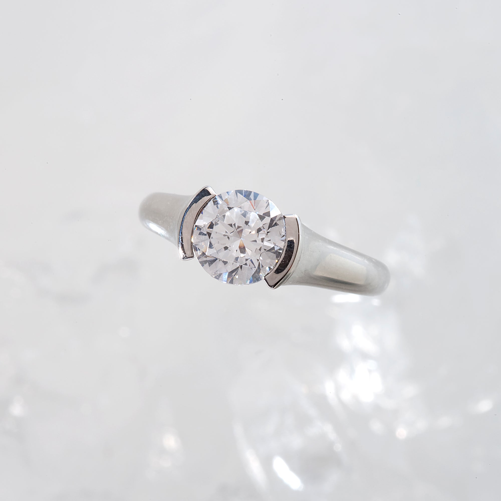 Diamond engagement ring featuring a round brilliant-cut diamond. and channel-set princess-cut diamonds. Custom-made to order for any size diamond or gemstone center stone. Available in 14K or 18K white, yellow, rose gold, and platinum. 